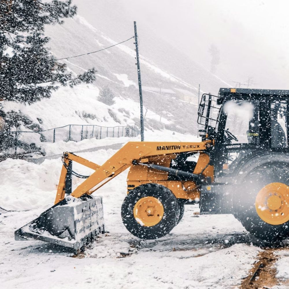 Skid steer loader using a bucket attachment to clear snow at a construction site