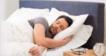 Man sleeping in bed next to an alarm clock representing worries that keep people up at night