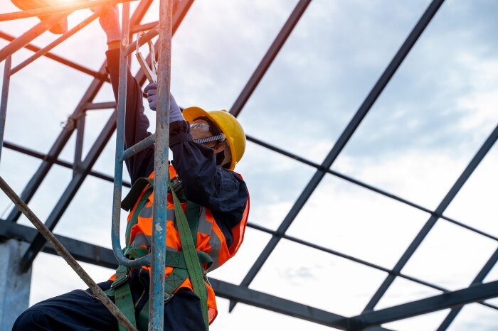Construction worker using ladder with fall protection equipment during ladder safety training program